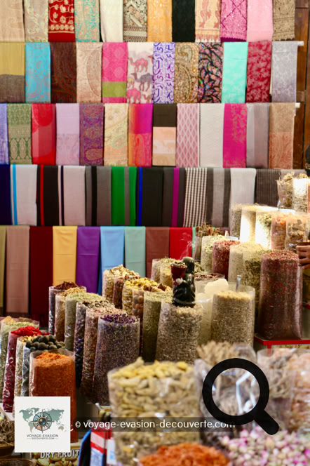 D'un côté, le souk du textile déploie ses galeries couvertes remplies de tissus colorés, de soies brodées, de pashminas et de cotons venus de toute l'Asie. Les étoffes pendent en cascades depuis les échoppes, créant un véritable arc-en-ciel permanent.