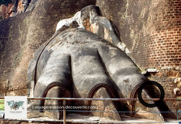 Vous arriverez à une terrasse connue sous le nom d'escalier du lion. De l'imposant lion, signe de  l'autorité royale, il ne reste que les pattes monumentales. C'est par cet escalier de fer zigzaguant à  flanc de rocher que l'on accède aux vestiges des palais, tout au sommet du rocher.  